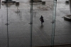 A woman exits the convention center in the rain. 